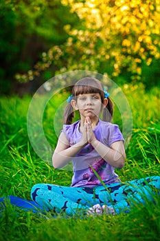 Beautiful girl doing yoga outdoors On green grass