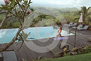 Beautiful Girl Doing Yoga On Poolside In Morning In Bali, Indonesia.