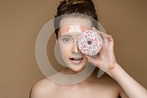 Beautiful girl with donut in hand and tinsel makeup