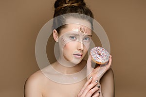 Beautiful girl with donut in hand and tinsel makeup