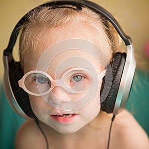 Beautiful girl with Down syndrome is listening to music on headphones