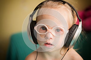 Beautiful girl with Down syndrome is listening to music on headphones
