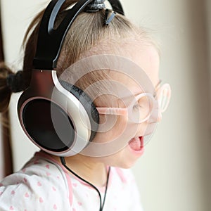 beautiful girl with Down syndrome is listening to music on headphones