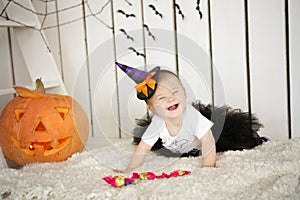 Beautiful girl with Down syndrome thoughtfully keeps finger in the mouth near the big pumpkin