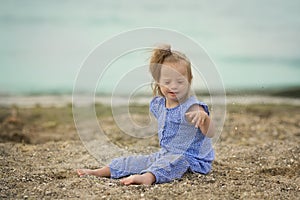 Beautiful girl with Down syndrome throwing sand on the seashore