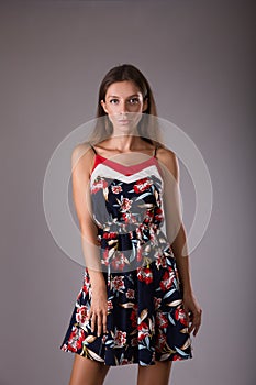 Beautiful girl in dress with floral print on grey background