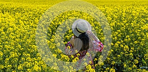 Beautiful girl with dress and hat in the Canola Fields.