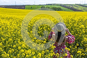 Beautiful girl with dress and hat in the Canola Fields.