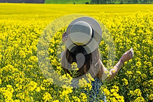 Beautiful girl with dress and hat in the Canola Fields.