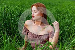 a beautiful girl in a dress sits in a green field