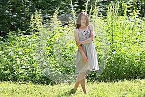 Beautiful girl in dress standing in woods amid tall grass