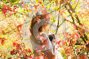 Beautiful girl drinking coffee in autumn wood. A cup with hot drink. Cosy mood. Red and yellow leaves. Beautiful nature. Stylish