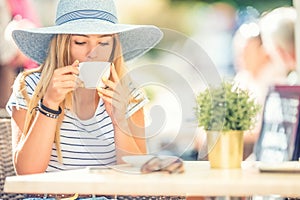 Beautiful girl drinking coffee in a cafe terrace. Summer portrait young woman