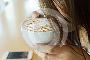 Beautiful girl drinking hot coffee or tea in coffee cafe