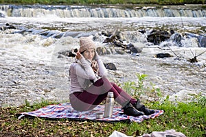 beautiful girl drinking tea near the river