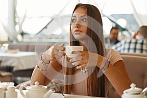 Beautiful girl drinking tea in a summer cafe.