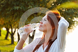 Beautiful girl is drinking water from a bottle