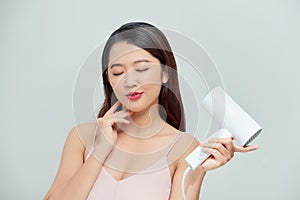 Beautiful girl drying her hair with hairdryer