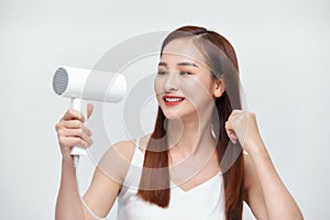 Beautiful girl drying her hair with hairdryer