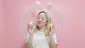 Beautiful girl in Easter bunny ears holding painted easter eggs on pink