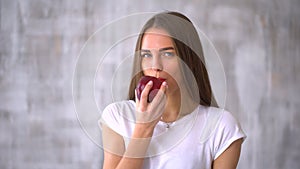 Beautiful girl eating an apple. Girl teenager with red apple. Portrait of young woman eating red apple.