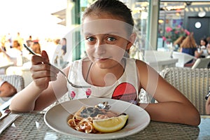 Beautiful girl eating sea fruit pasta at an italian restaurant