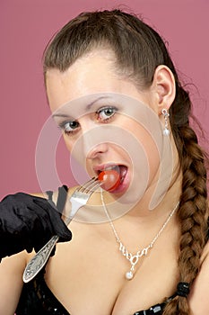 Beautiful girl eating small tomato