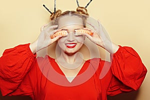 Beautiful girl eating sushi on a white plate. A woman in a red dress and red lips eats sticks of sushi with shrimps. Model closes