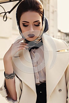 Beautiful girl in elegant beige coat and silk scarf on head