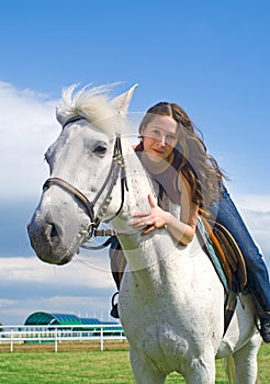 Beautiful girl embraces a white horse
