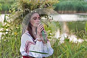 Beautiful girl in embroidery shirt and wreath of wild flowers.