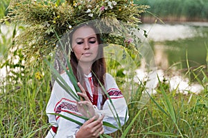 Beautiful girl in embroidery shirt and wreath of wild flowers.