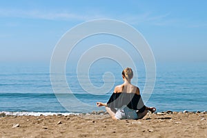 A beautiful girl is engaged in yoga on the beach against the background of the sea. Health and sports. A woman on the ocean shore