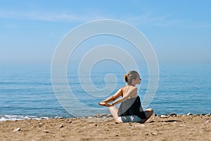 A beautiful girl is engaged in yoga on the beach against the background of the sea. Health and sports. A woman on the ocean shore