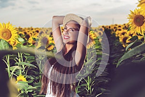 Beautiful girl enjoying nature on the field of sunflowers at sunset