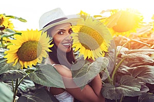 Beautiful girl enjoying nature on the field of sunflowers at sunset
