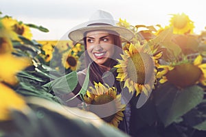 Beautiful girl enjoying nature on the field of sunflowers at sunset