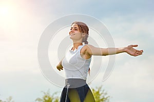 Beautiful girl enjoying the sun with her arms outstretched in the field against the sky