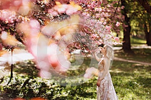 Beautiful girl enjoys the scent of flowering tree. Portrait of beautiful woman with blooming cherry tree - girl inhales the scent