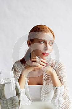 Beautiful girl of European appearance.Red hair with a touch of honey.Beauty shooting. A container of water. A symbol of