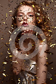 Beautiful girl in an evening dress and gold curls. Model in New Year`s image with glitter and tinsel.