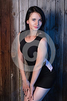 Beautiful girl in evening dress, the model poses against a wooden wall,