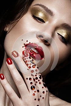 Beautiful girl with evening make-up, red lips in rhinestones and design manicure nails. beauty face.