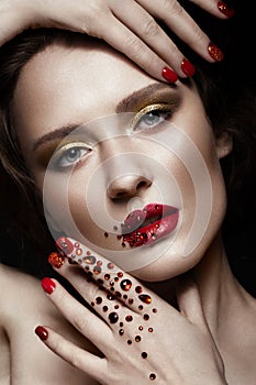 Beautiful girl with evening make-up, red lips in rhinestones and design manicure nails. beauty face. photo