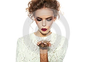 Beautiful girl with evening makeup blow gold sequins