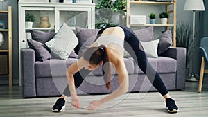 Beautiful girl exercising at home bending forward stretching legs and back.