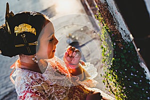 Beautiful girl fallera wearing the traditional Valencian costume of Fallas, during a beauty session and posing outdoors photo