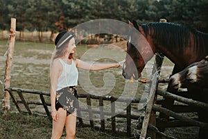 Beautiful girl on the farm feeds the horse. Woman holding farm animals in the forest. Life in the village, a beautiful brunette