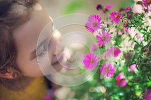 Beautiful girl farmer woman smells the aroma of blooming pink flowers in a flower garden