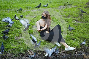 Beautiful girl feeds bread to pigeons in a city Park in the summer
